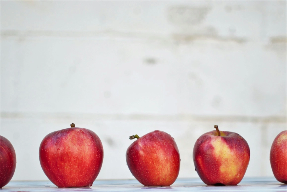 A row of red apples with one slightly misshapen apple in the center