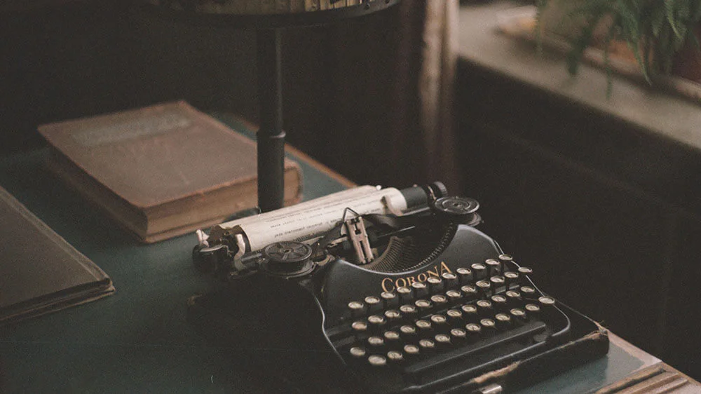 Classic black typewriter sitting on table in front of old books