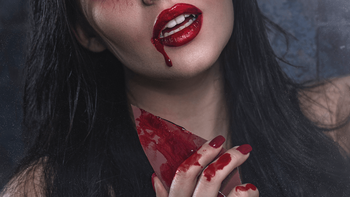 The lower half of a vampire woman with red lipstick and blood trailing down her face and neck